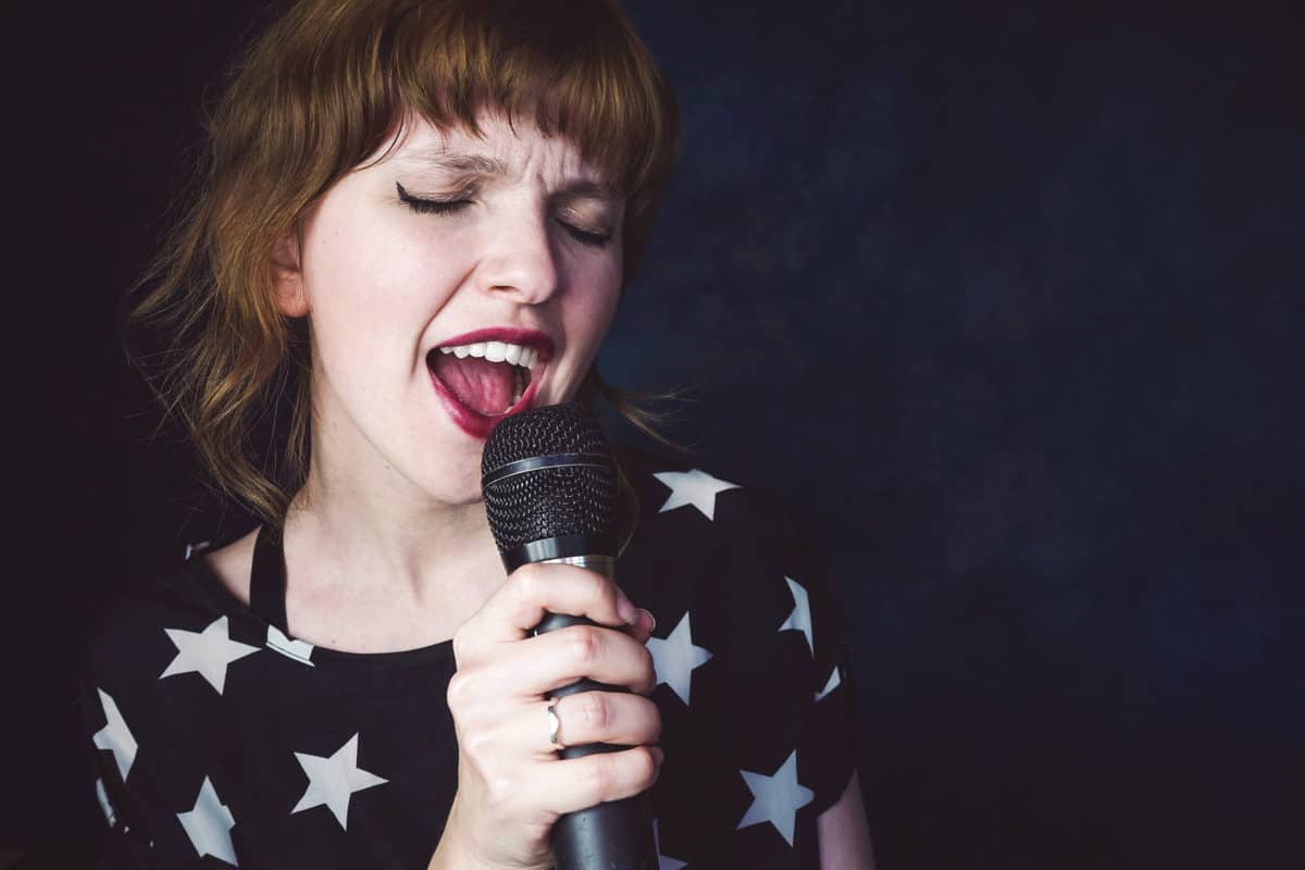 Young woman singing a song with a karaoke microphone